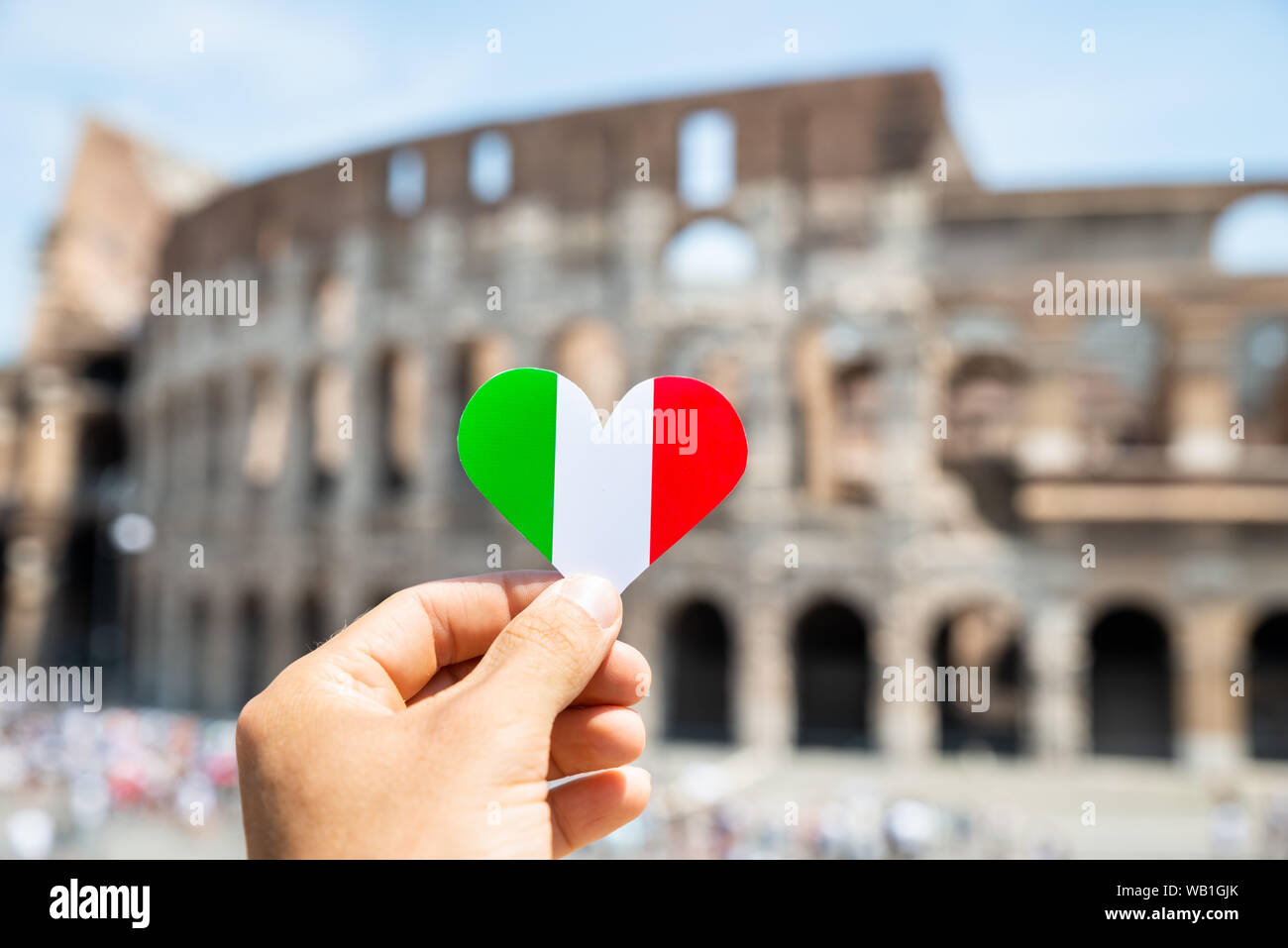 Donna che mantiene a forma di cuore Bandiera Italiana davanti al Colosseo, Italia Foto Stock