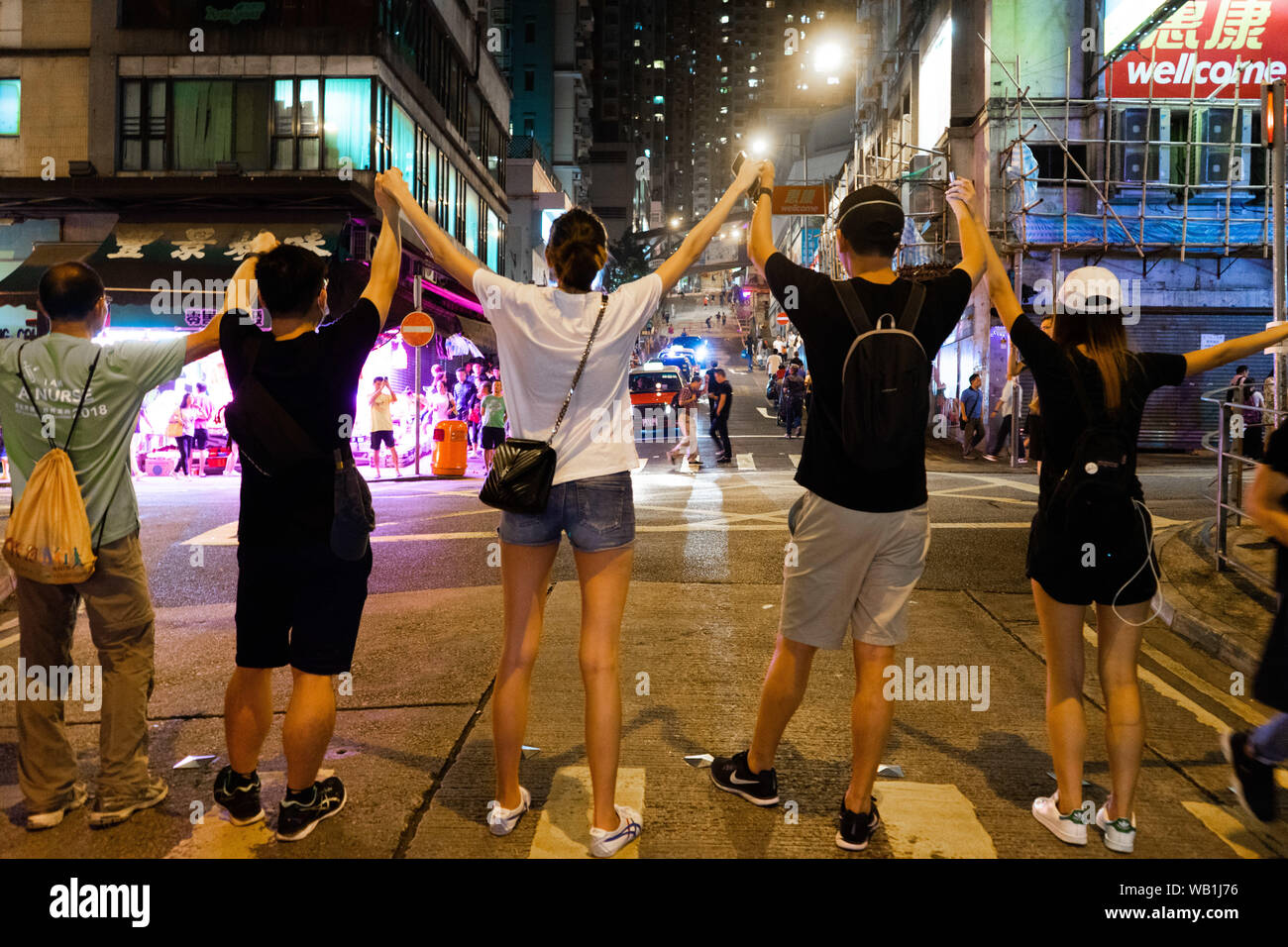 Hong Kong manifestanti di diversa età tenere le mani attraverso la strada in una trafficata area residenziale locale per formare la catena umana per chiamare per la democrazia. Essi avrebbero retreat torna alla pavimentazione stradale quando il semaforo per i pedoni diventa rosso per consentire il passaggio del traffico.Migliaia di Hong Kong manifestanti link le mani per formare catene umane in tutta la città di chiamare per la democrazia. Le catene che tracciate tre percorsi della metropolitana, ammontano a circa 40 km (25 miglia) di lunghezza. I manifestanti hanno detto di essere stati ispirati da "Via Baltica", quando milioni di persone ha creato una catena attraverso tre paesi (Estonia, Lettonia e Lithua Foto Stock