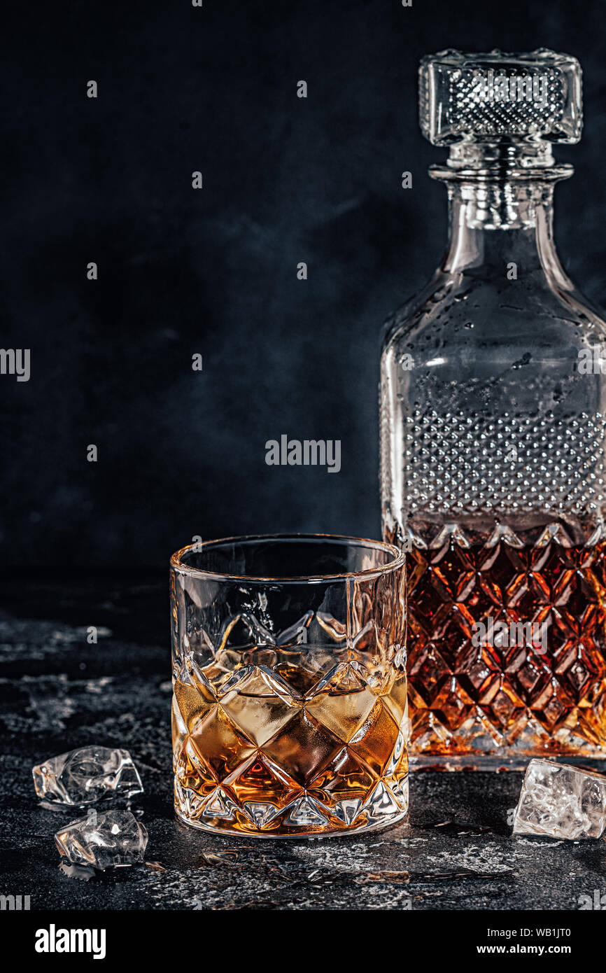 Bicchieri di whiskey con un decantatore quadrato su una pietra nera dello sfondo. Foto Stock