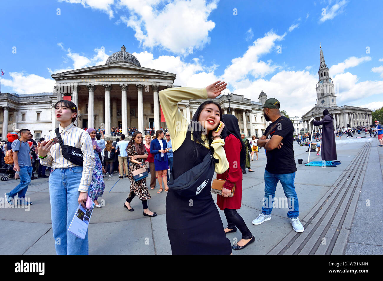 Londra, Inghilterra, Regno Unito. I turisti giapponesi in Trafalgar Square - Galleria Nazionale dietro Foto Stock