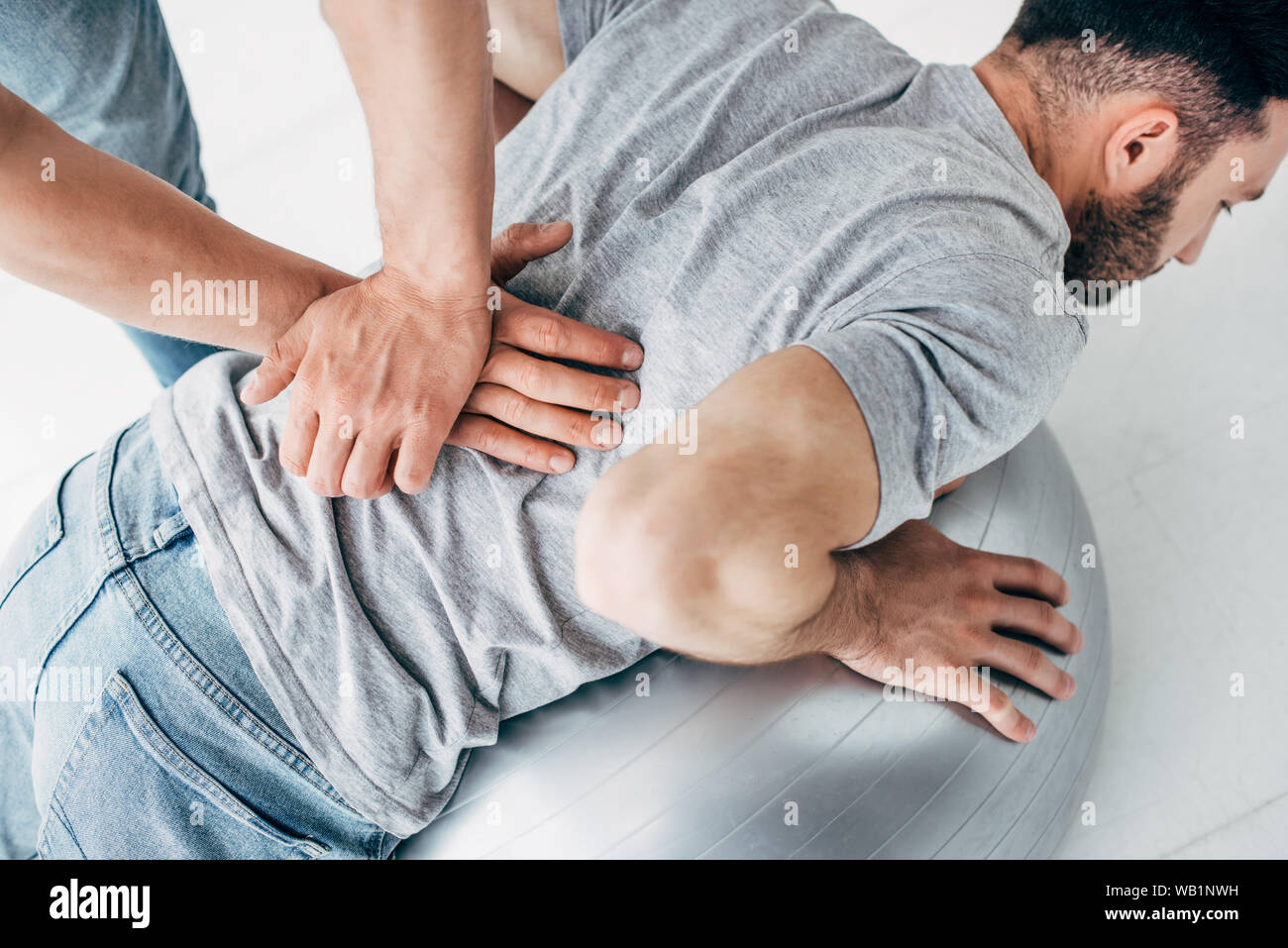 Massaggio chiropratico retro dell uomo disteso sulla sfera di fitness Foto Stock