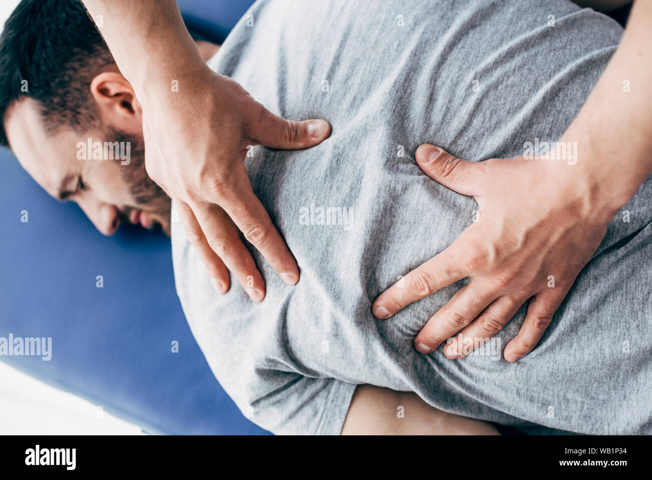 Fisioterapista il massaggio schiena dell uomo disteso sul lettino da massaggio in ospedale Foto Stock