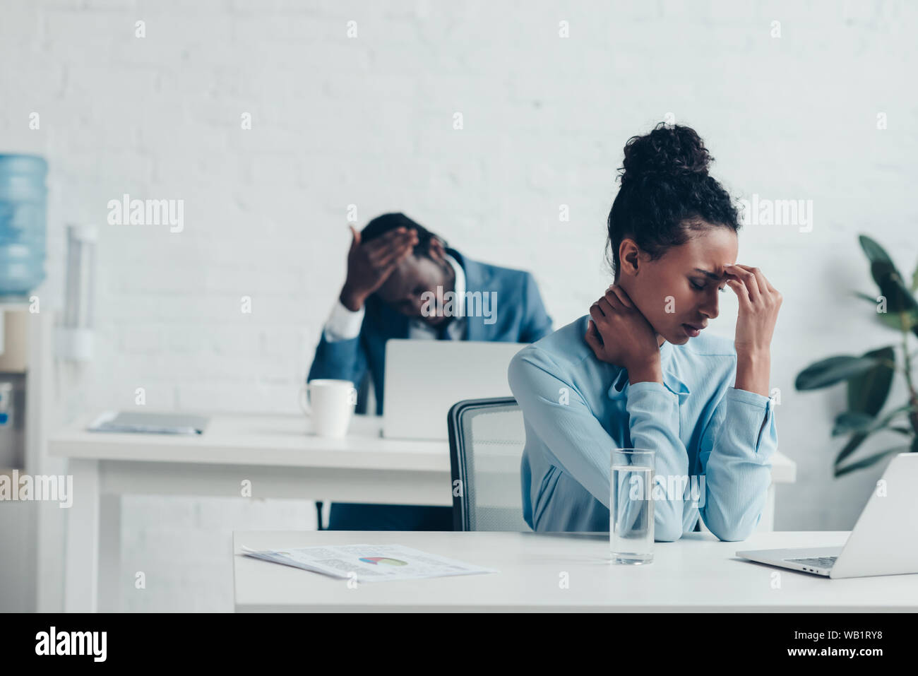 African American managers seduti nei luoghi di lavoro e che soffrono di mal di testa Foto Stock