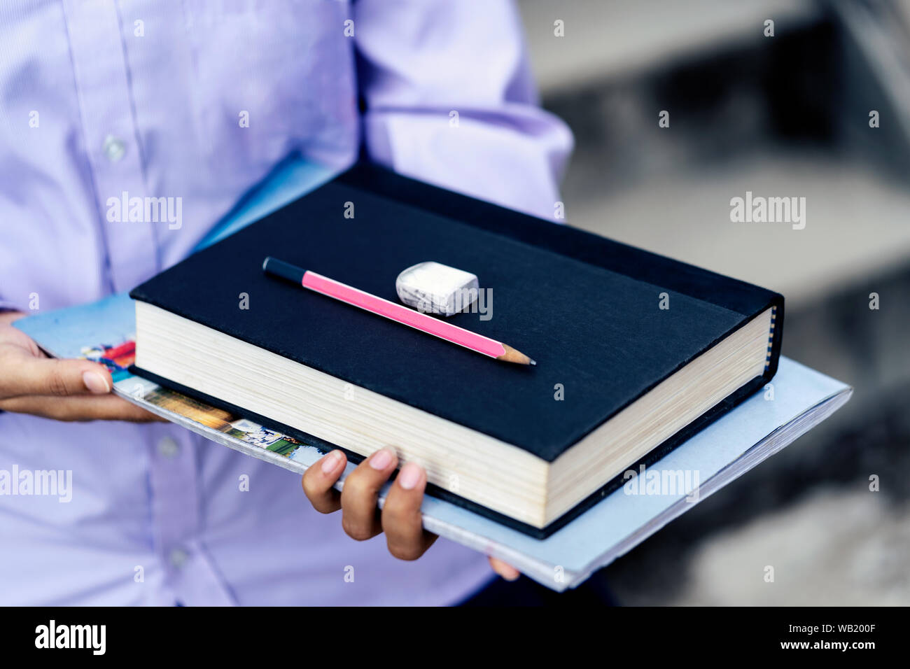 Una ragazza giovane studente in possesso di una pila di libri, matita, eraser. Concetto di prestito di istruzione, istruzione superiore dello schema, borsa di studio ecc. Foto Stock