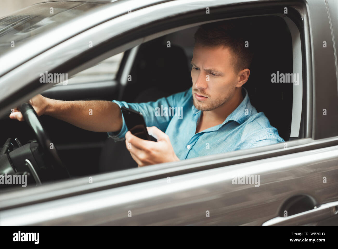 Giovane uomo bello rigidi unsafely controllando il suo smartphone durante la corsa Foto Stock