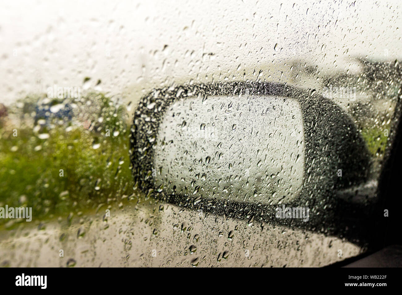 La pioggia al di fuori della finestra di auto, lo specchio in una pioggia Foto Stock