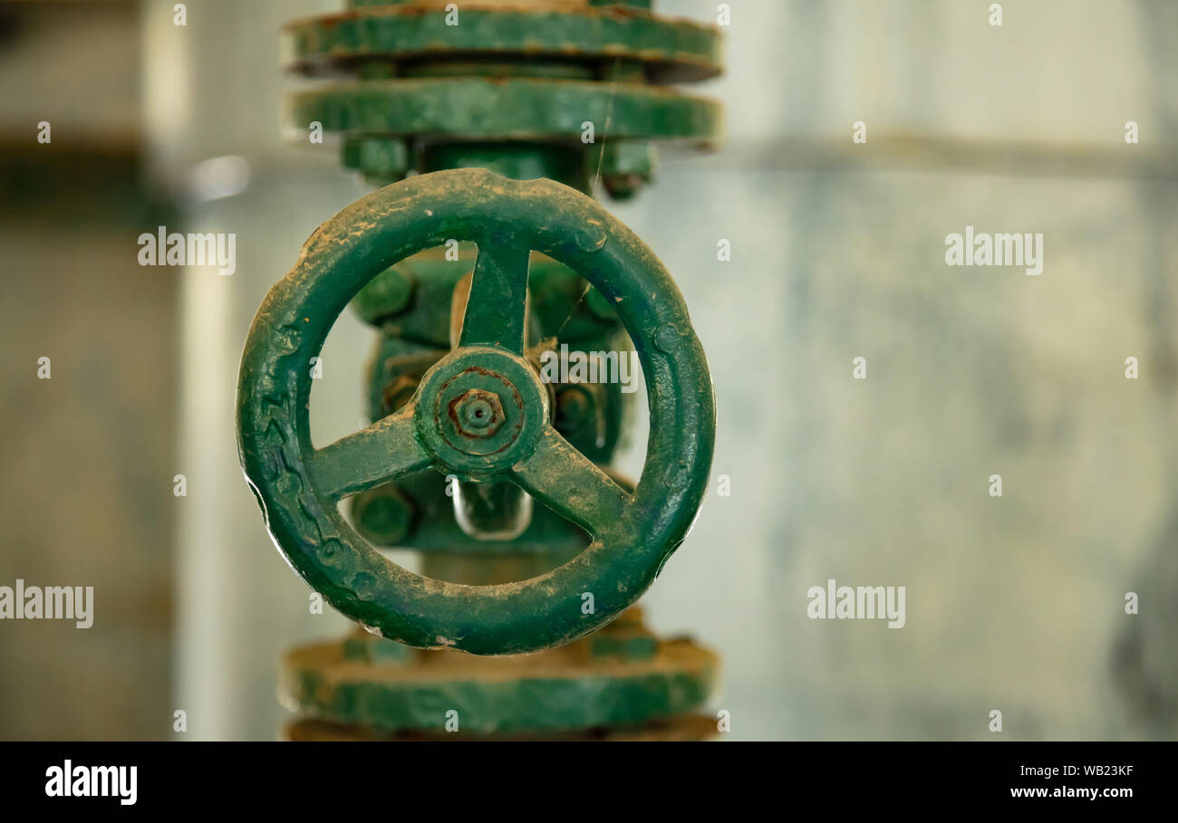 Condutture industriali e la valvola si chiudono, la sfocatura dello sfondo. Vecchio arrugginito apparecchiature di controllo, impianto carburante industry Foto Stock