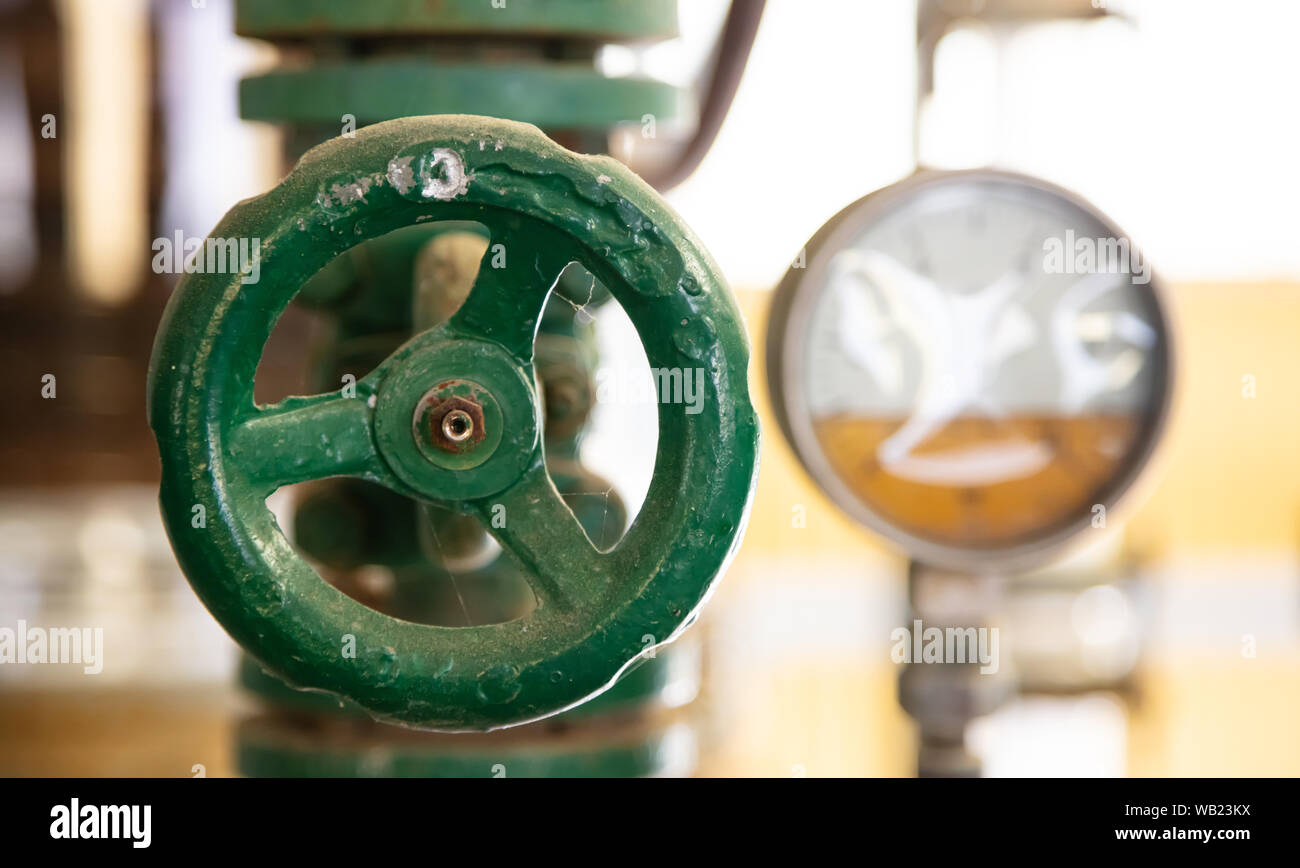 Condutture industriali e la valvola si chiudono, la sfocatura dello sfondo. Vecchio arrugginito apparecchiature di controllo, impianto carburante industry Foto Stock