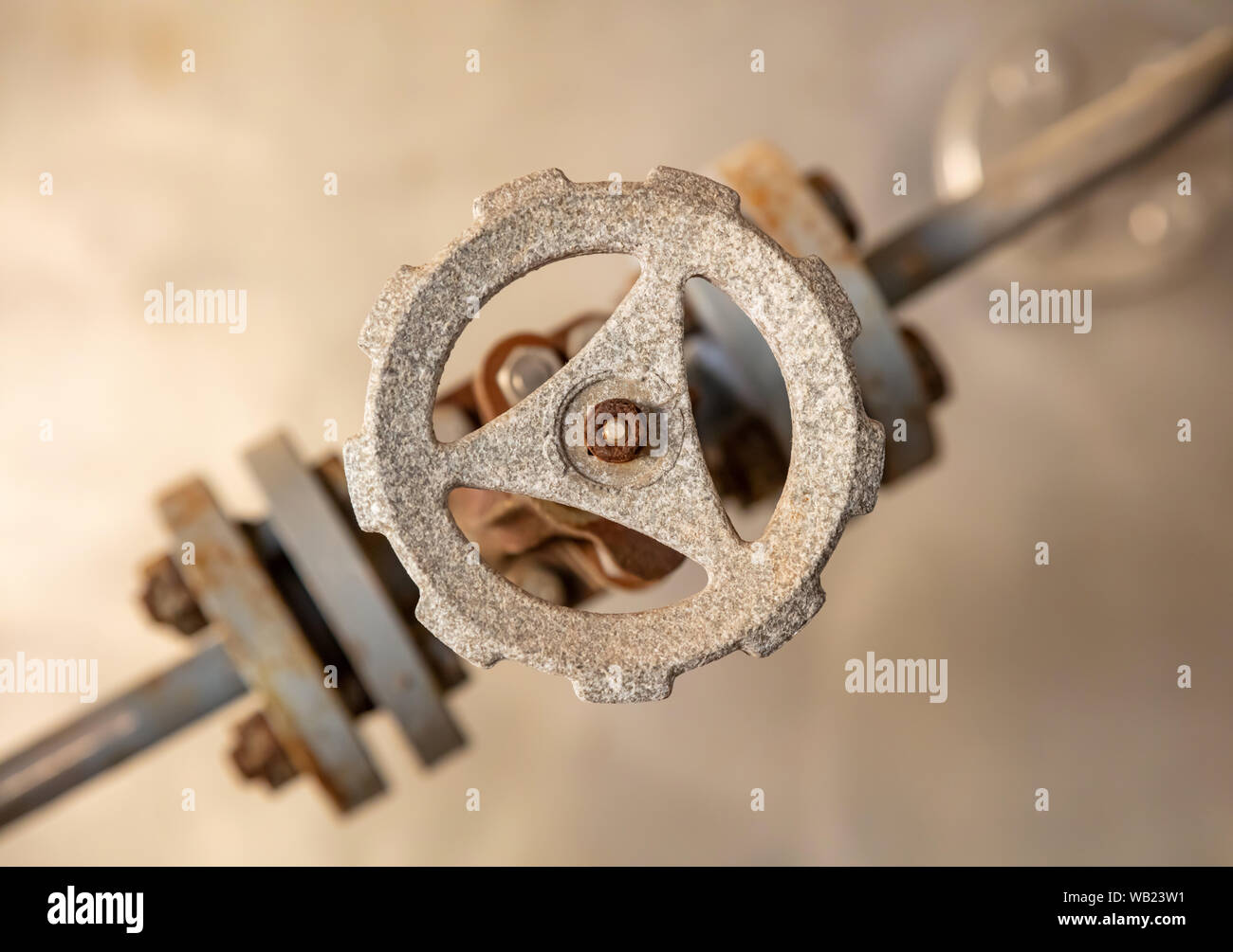 Condutture industriali e la valvola si chiudono, la sfocatura dello sfondo. Vecchio arrugginito apparecchiature di controllo, abbandonata impiantistica industriale Foto Stock