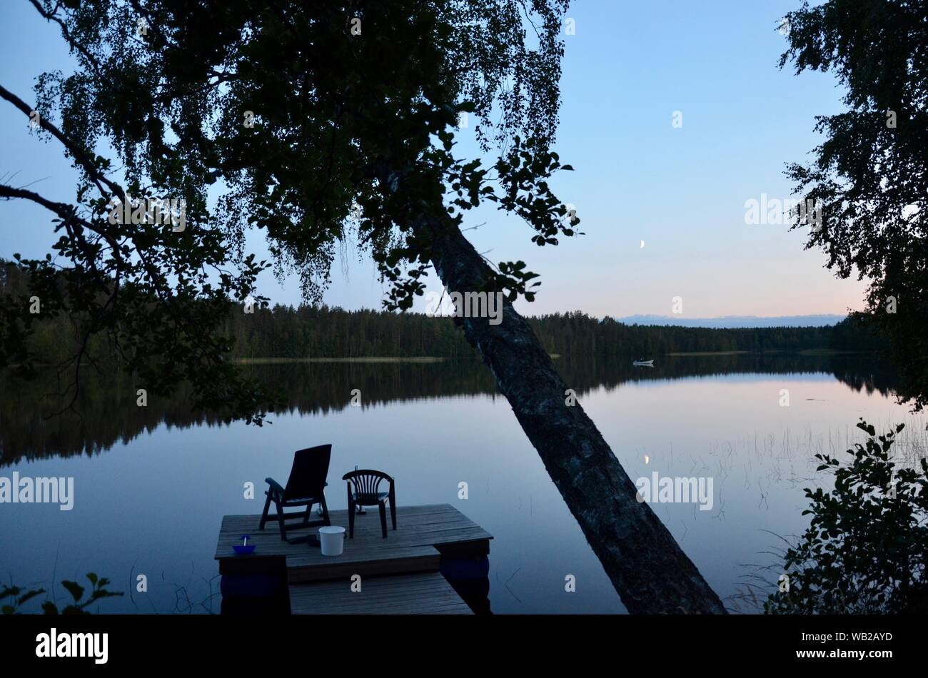 Serata tranquilla scena con sedie vuote sul pontile sul lago calmo Sarkjarvi, Finlandia. Foto Stock