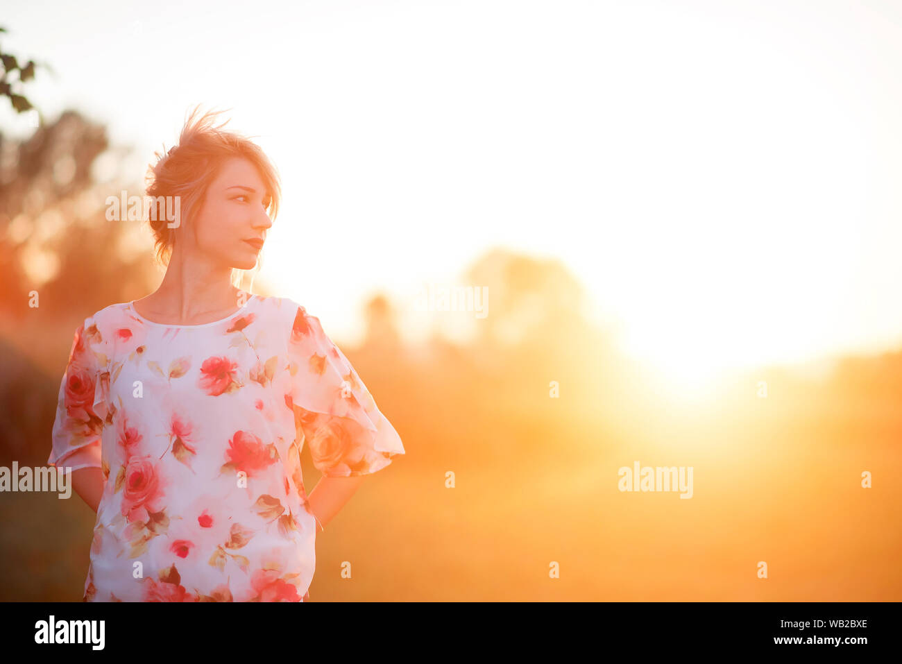 Giovane donna in camicia floreale in presenza di luce solare Foto Stock