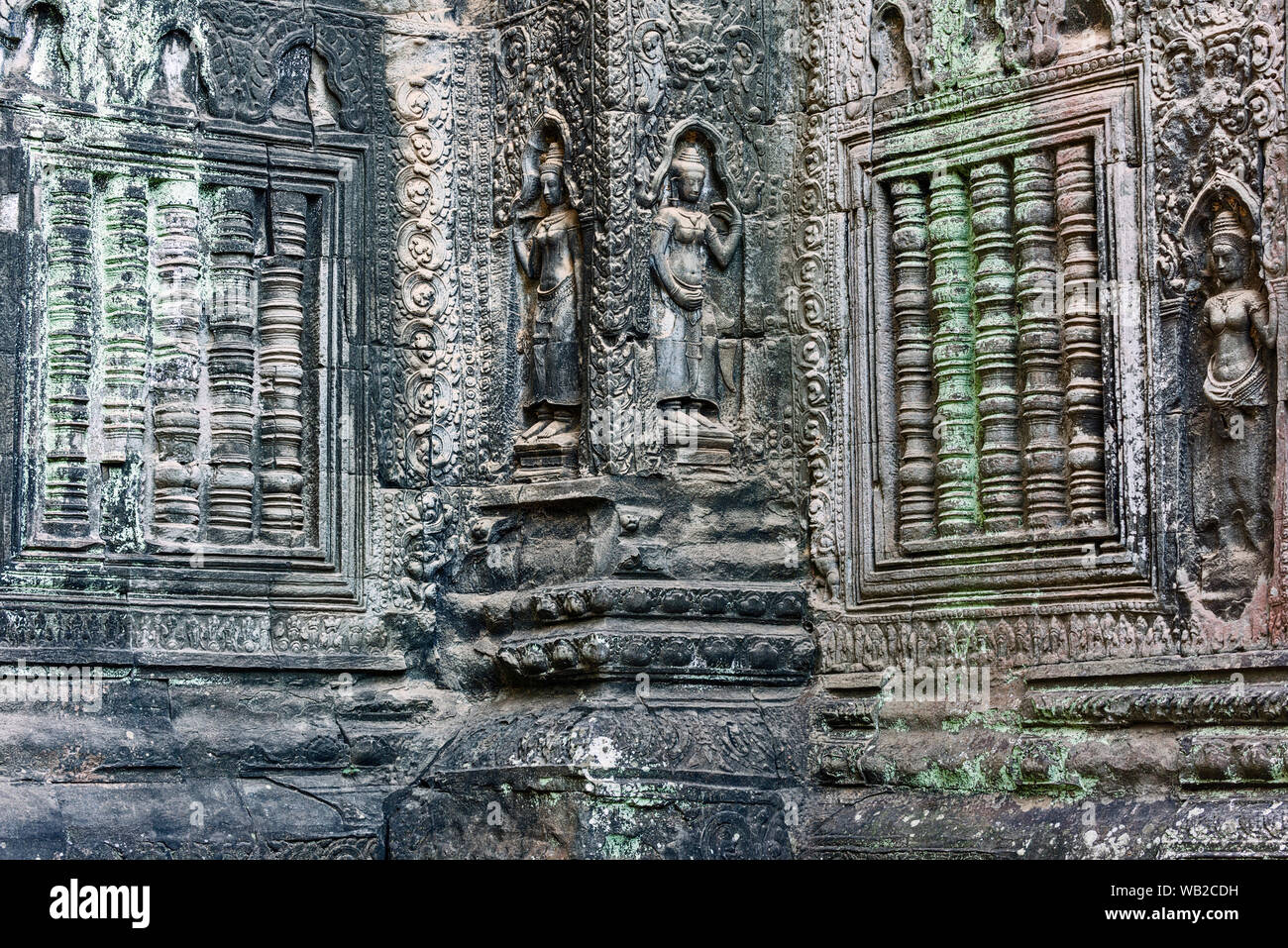 In arenaria scolpite in bassorilievo Apsaras (celesti di fanciulle) e scolpita in pietra barre finestra a Ta Prohm. Siem Reap, Cambogia. Foto Stock