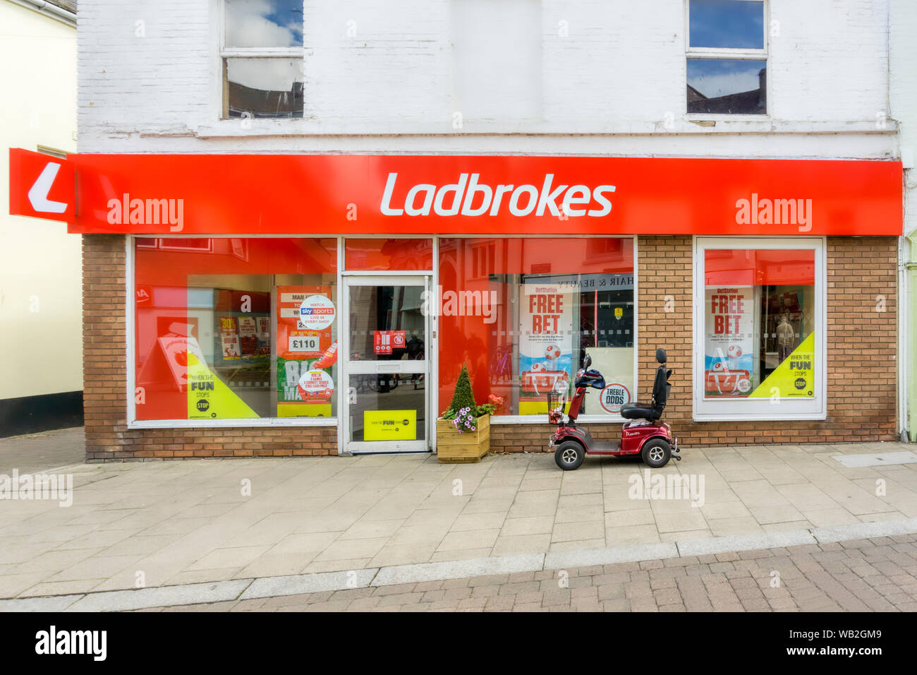 Una mobilità scooter parcheggiate fuori a Ladbrokes betting shop. Foto Stock