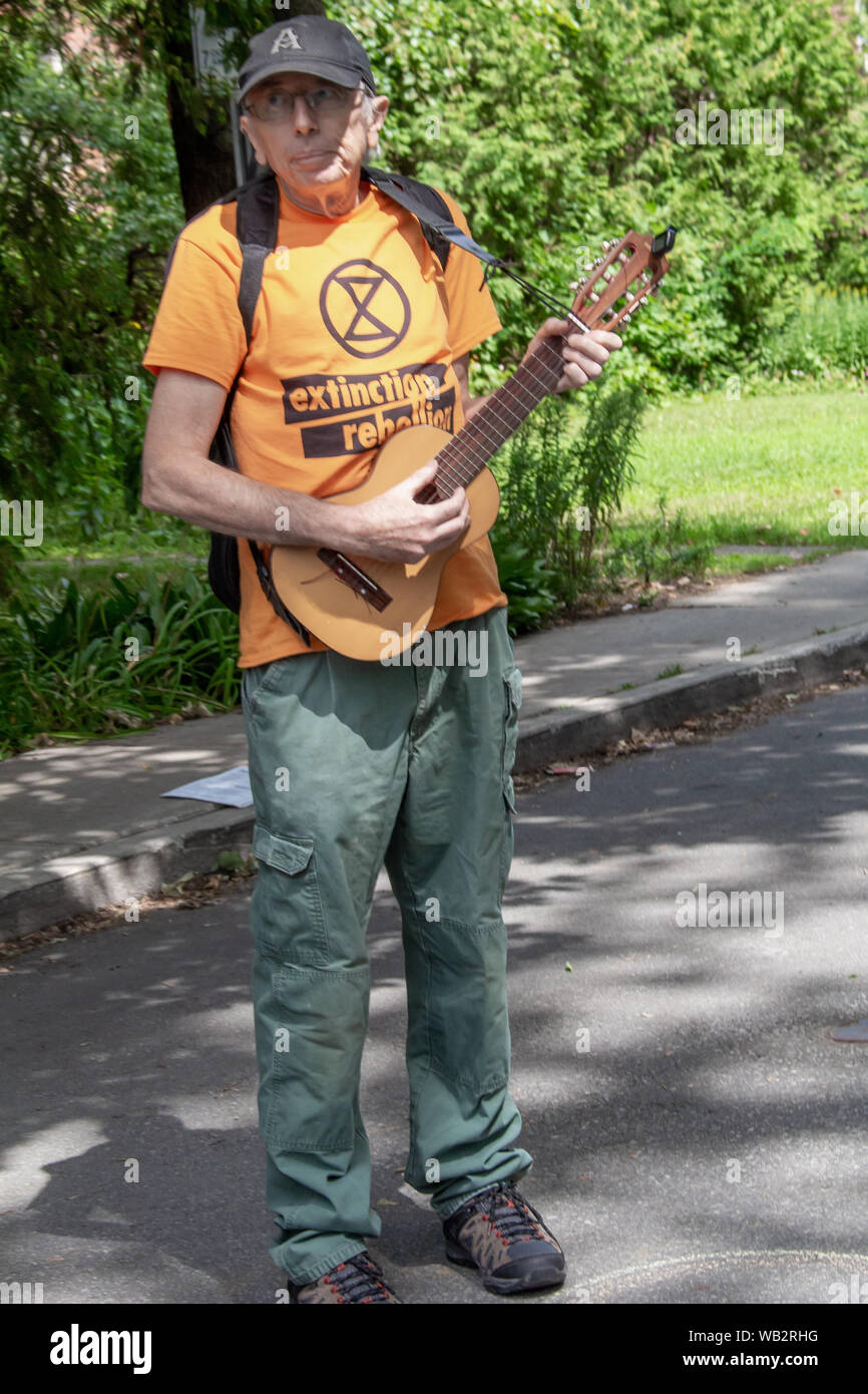 Un attivista dal gruppo estinzione della ribellione sta giocando un guitalele durante una manifestazione di protesta. Foto Stock