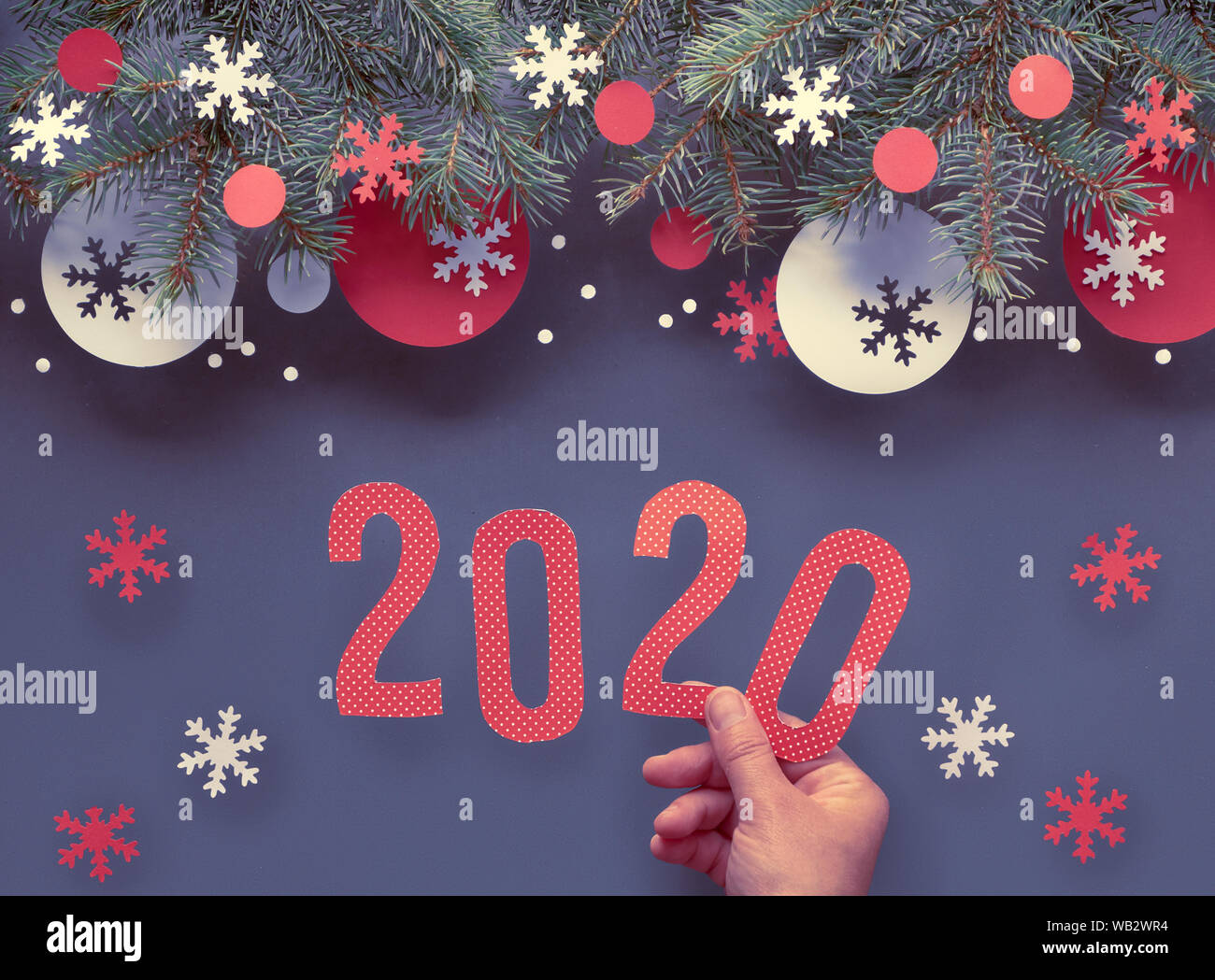 Mano azienda numero 2020, Natale sfondo con ramoscelli di abete rosso e bianco decorazioni di carta. Appartamento laico, vista dall'alto sulla astratta scuro dello sfondo. Foto Stock