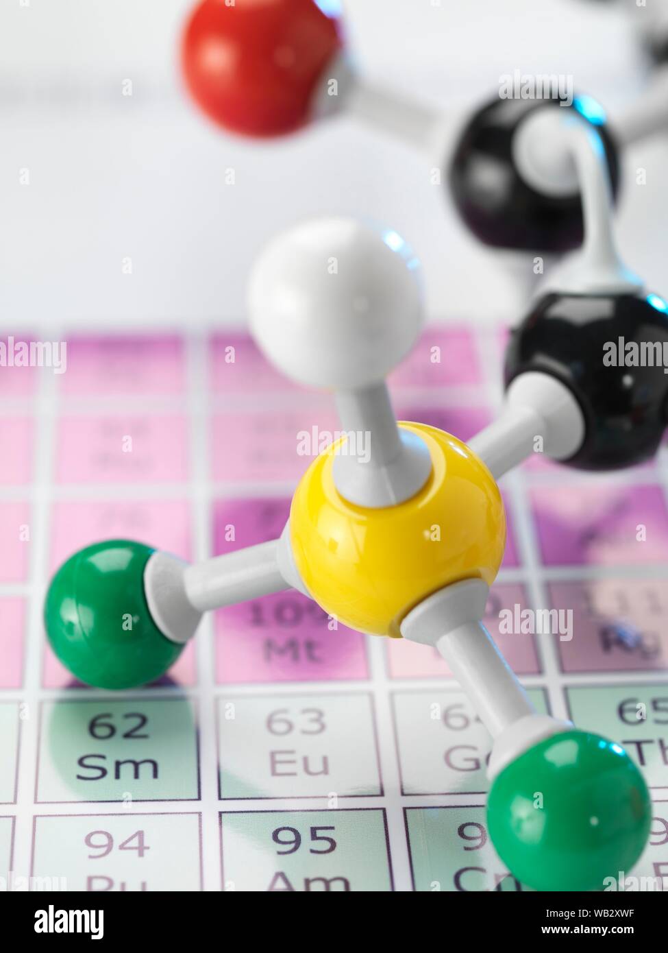 Chimica, immagine concettuale. Sfera e stick modello molecolare seduto su una tavola periodica Foto Stock