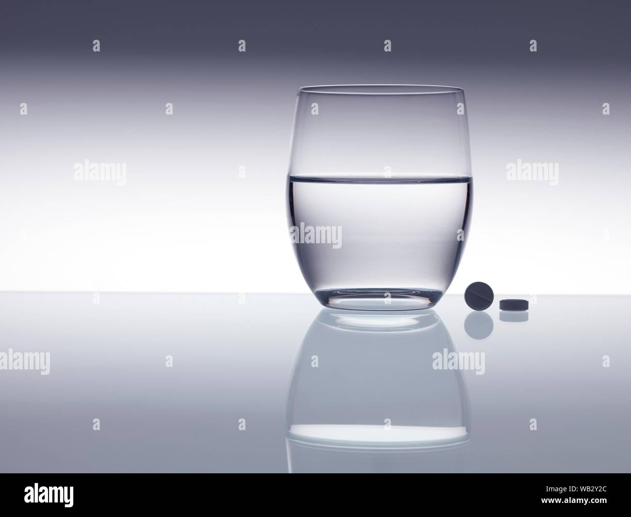 Compresse accanto a un bicchiere d'acqua. Foto Stock