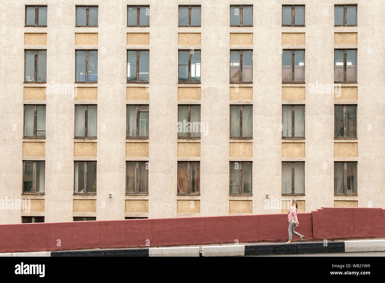 Donna walkng davanti a un edificio a Minsk, in Bielorussia. Foto Stock