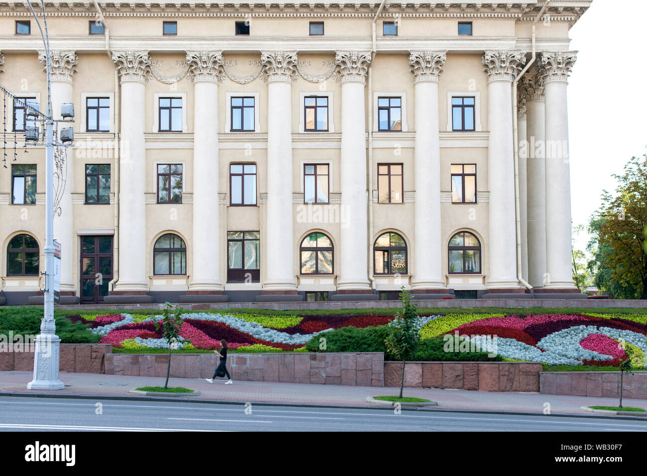 Donna che cammina davanti a un edificio sul Viale Indipendenza (Praspiekt Niezaliežnasci) a Minsk, in Bielorussia. Foto Stock