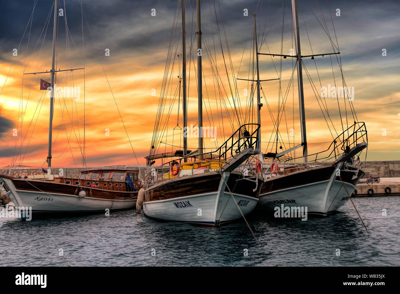 Tre bei yacht sedersi al dock in Kas, la Turchia come il sole illumina in background Foto Stock