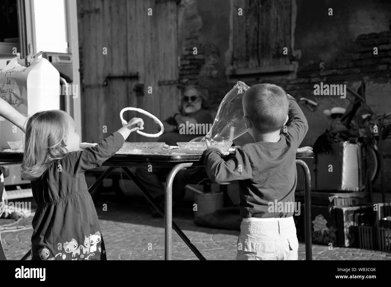 Due bambini nella piazza di insufflazione di bolle di sapone e divertirsi. In stile vintage. Foto Stock