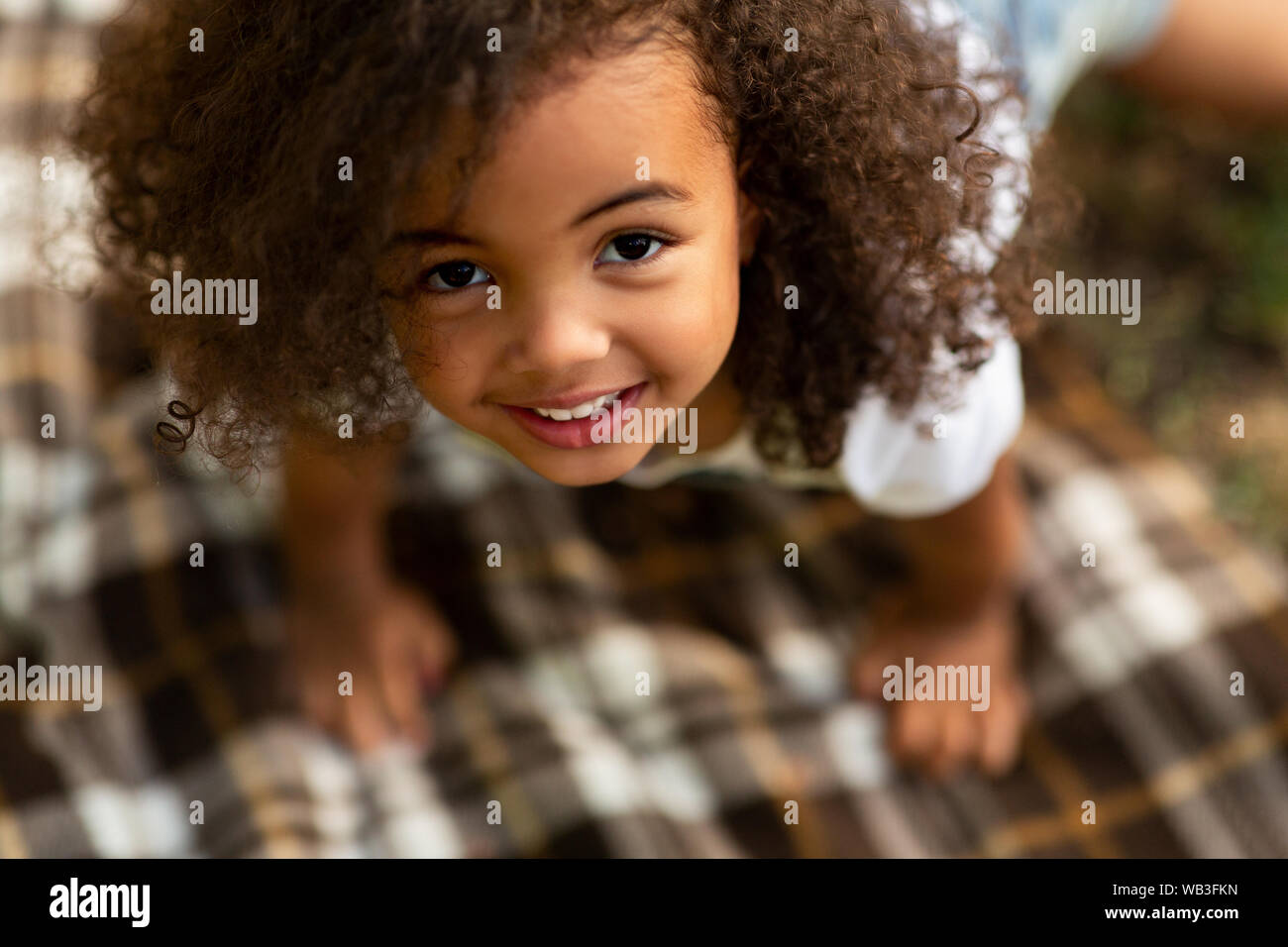 Carino bambina gioca su una coperta e guardando in alto Foto Stock