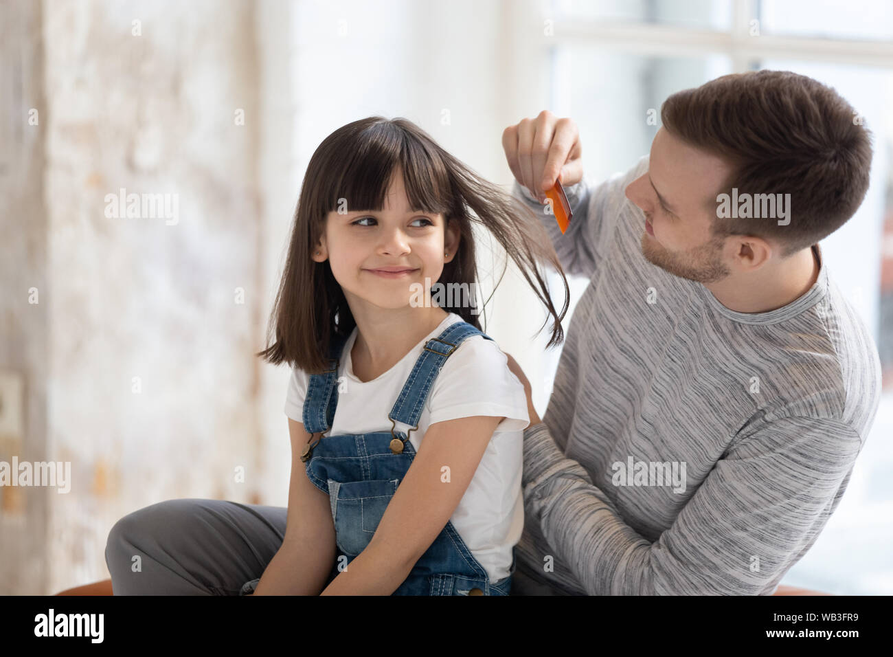 Amare giovane padre facendo spazzolare i capelli della cute kid figlia Foto Stock