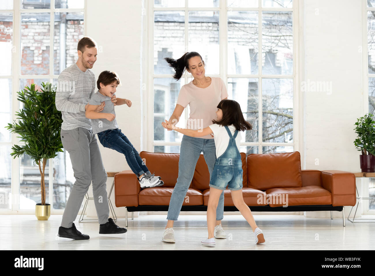 Genitori felici e bambini ridere ballare insieme in salotto Foto Stock