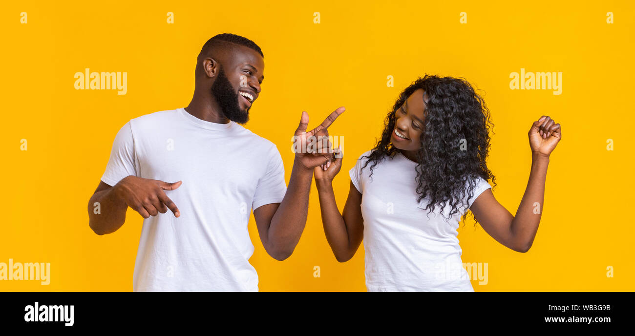 Gioiosa americano africano coppia danzante su giallo di sfondo per studio Foto Stock