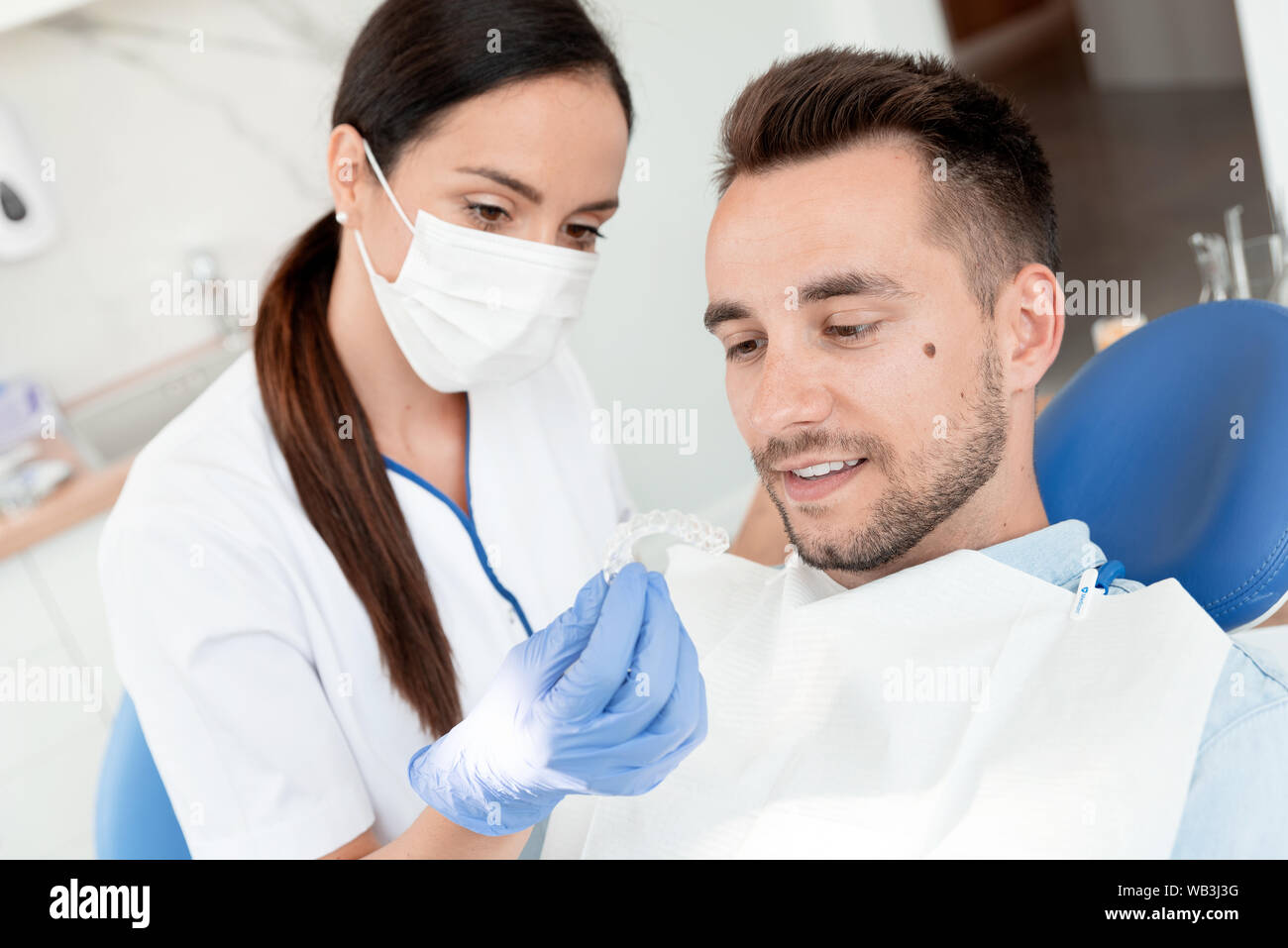 Dentista mostra invisibile allineatore di bretelle. Consultazione dentale in una clinica ortodontica Foto Stock