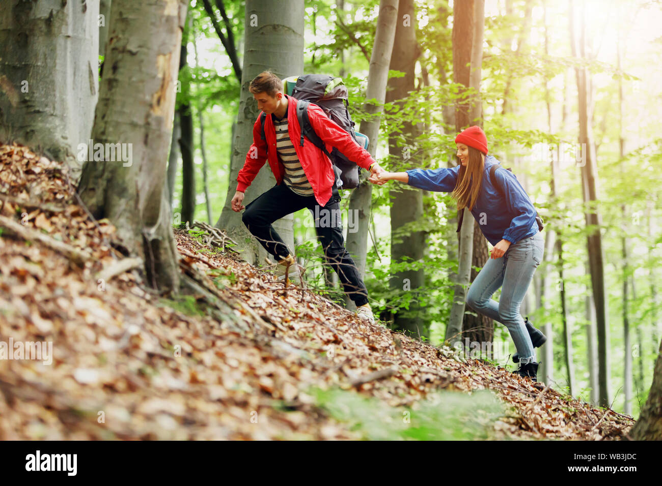 Escursionista guy dà una mano alla ragazza mentre passeggiate in montagna, guida e concetto di amicizia Foto Stock