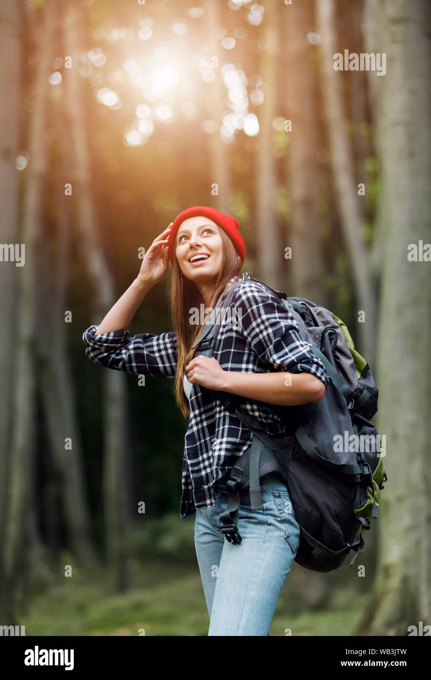 Giovane donna con zaino tenendo la mano vicino alla testa mentre si ammira la natura in estate Foto Stock