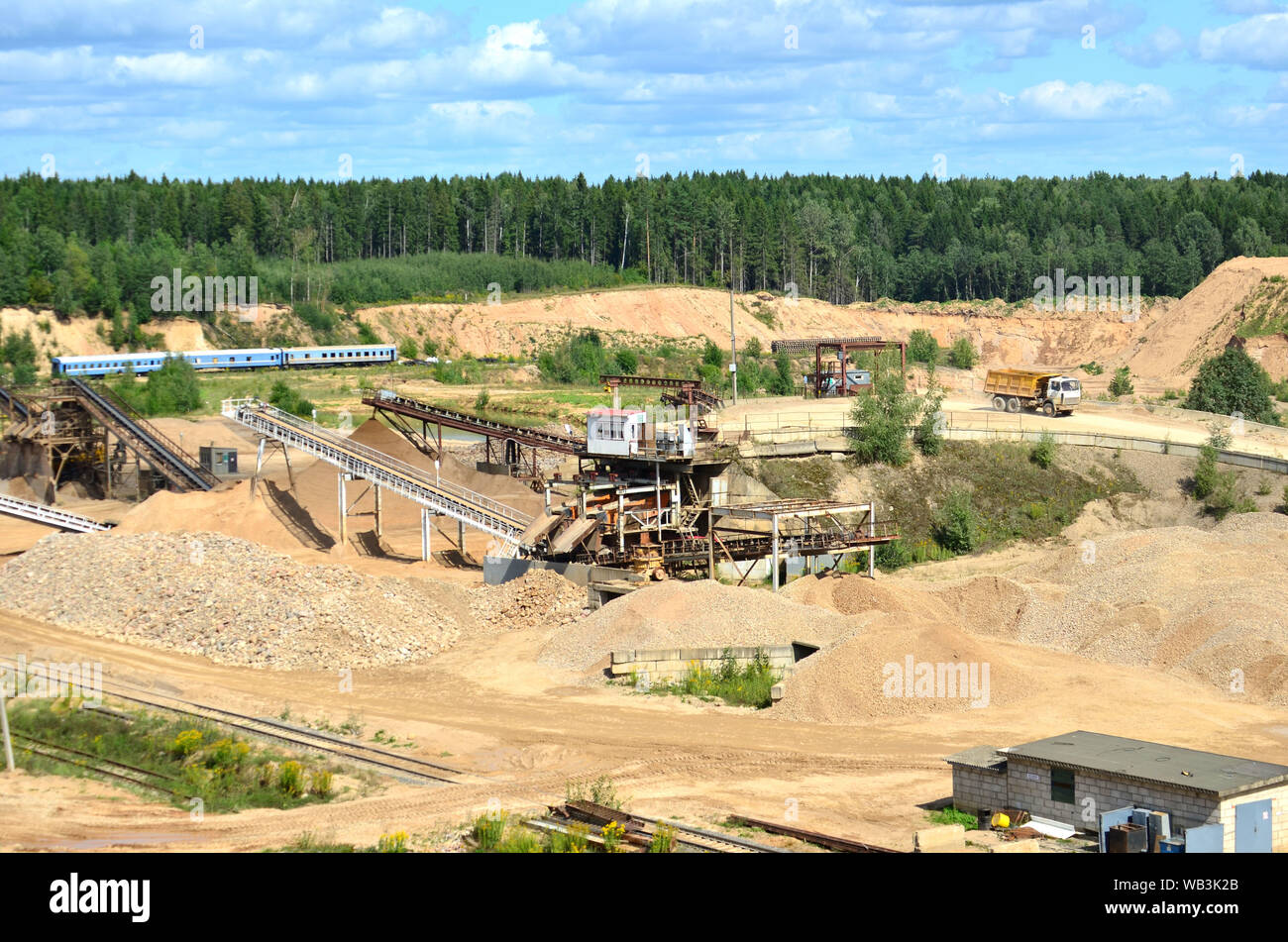 Vista sulla cava di data mining per la produzione di pietrisco, sabbia e ghiaia. Frantoio impianto con nastro trasportatore, procedimento di frantumazione e macinazione di pietra. Wo Foto Stock