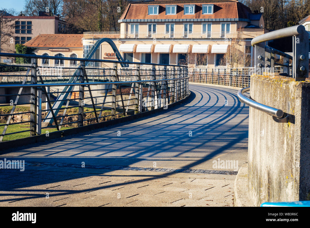 Bad Kissingen in Baviera, Germania - 16 Febbraio 2019: una rana in prospettiva di un moderno ponte che conduce sulla Saale Francone con edifici in Foto Stock