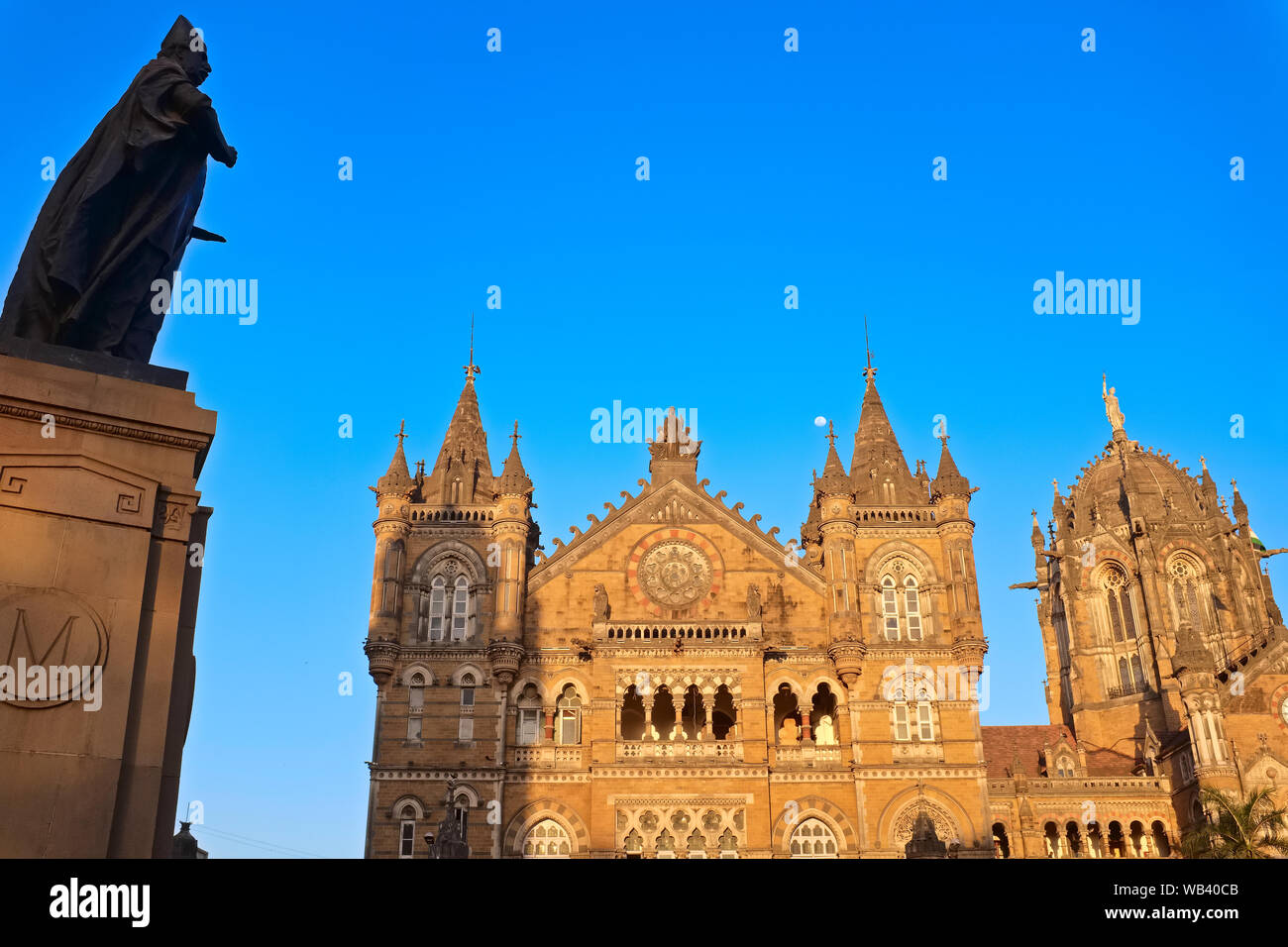 Chhatrapati Shivaji Maharaj Terminus (r), Mumbai della più trafficata stazione ferroviaria, e una statua di Sir Pherozeshah Mehta, in piedi di fronte ad un edificio di BMC Foto Stock