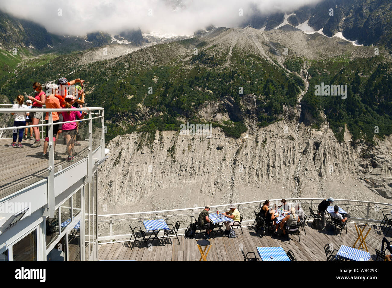 I turisti sulle terrazze del Montenvers stazione ferroviaria con le Aiguilles du Dru, una montagna del massiccio del Monte Bianco, Chamonix, alpi, Francia Foto Stock