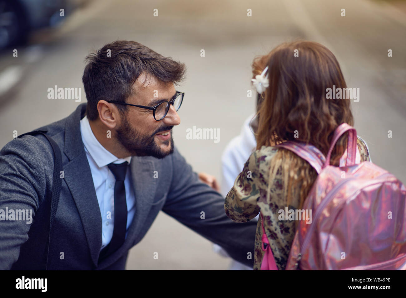 Felice giorno di ritorno a scuola. Padre sorridente prendendo il bambino alla scuola primaria. Foto Stock