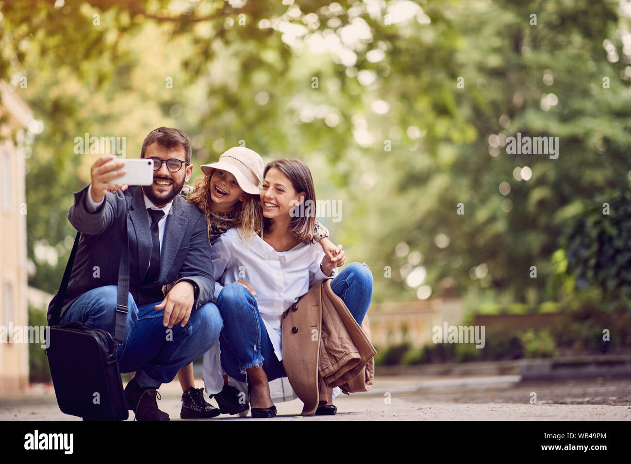 Genitori felici con la loro figlia dopo la scuola facendo una foto, Foto Stock