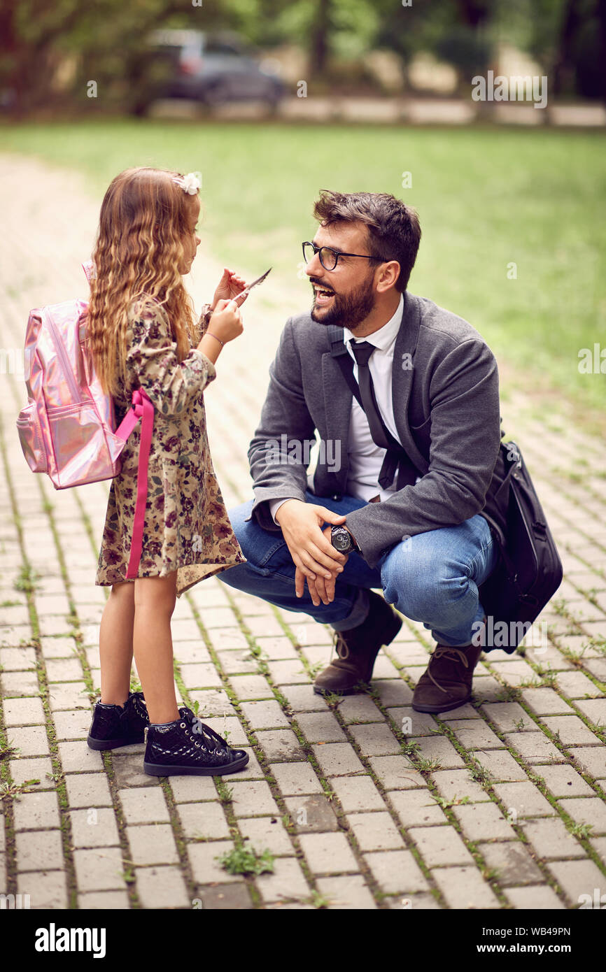 Sorridente padre business prendendo il bambino alla scuola primaria. Foto Stock