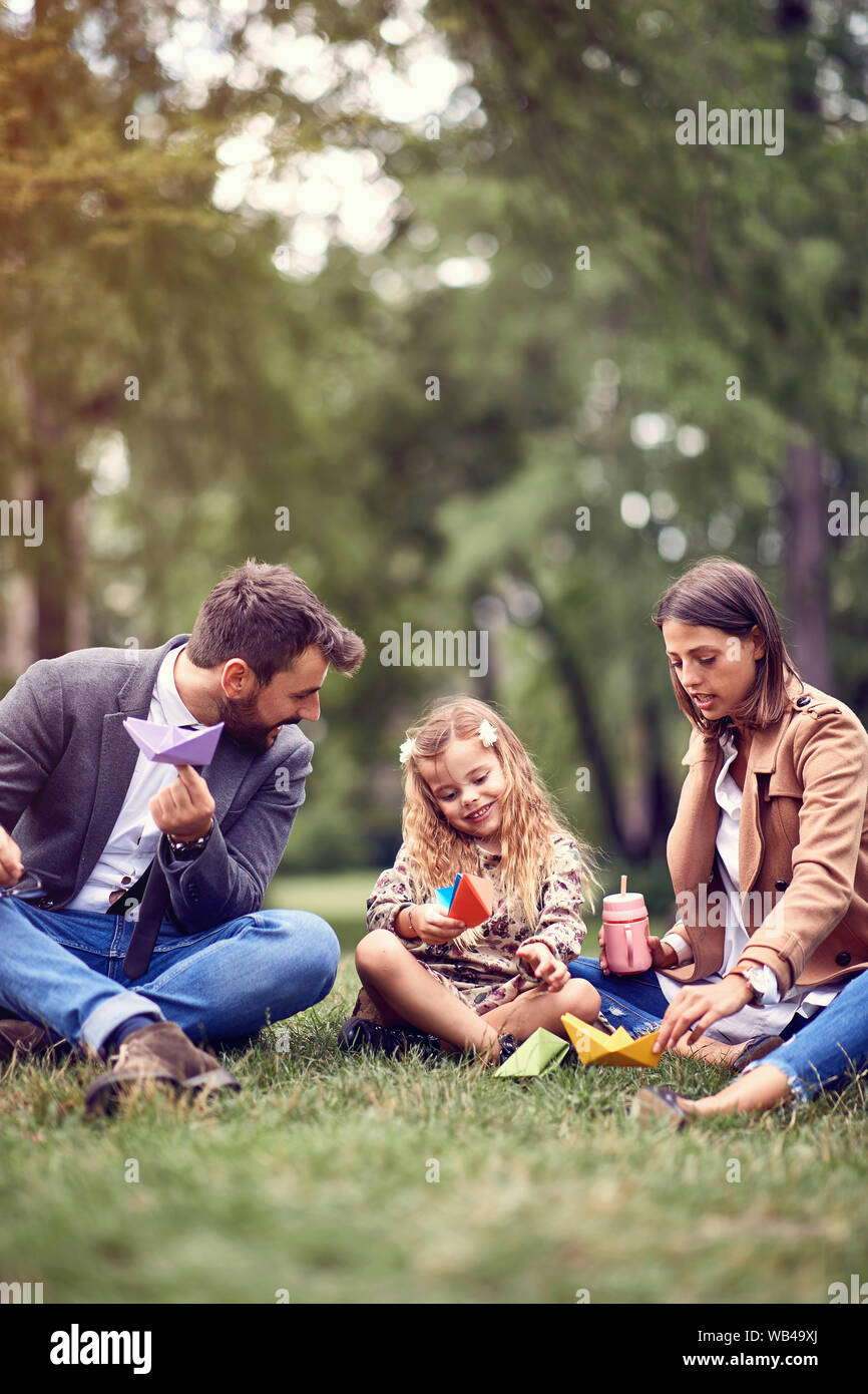 Carino figlia con la loro azienda madre e padre seduto e appoggiato al parco. Foto Stock