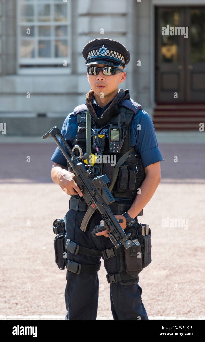 Armati di sesso maschile la Metropolitan Police officer portando una pistola fuori Buckingham Palace nella City of Westminster, Londra, Inghilterra, Regno Unito. Foto Stock
