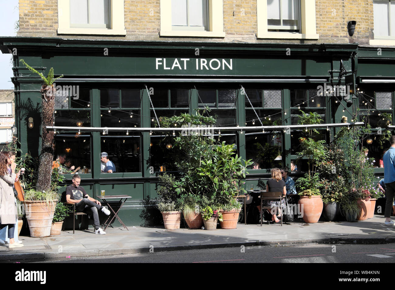 Ferro piatto di pub e la gente di turisti in estate su strada commerciale in Spitalfields East London E1 Inghilterra UK KATHY DEWITT Foto Stock