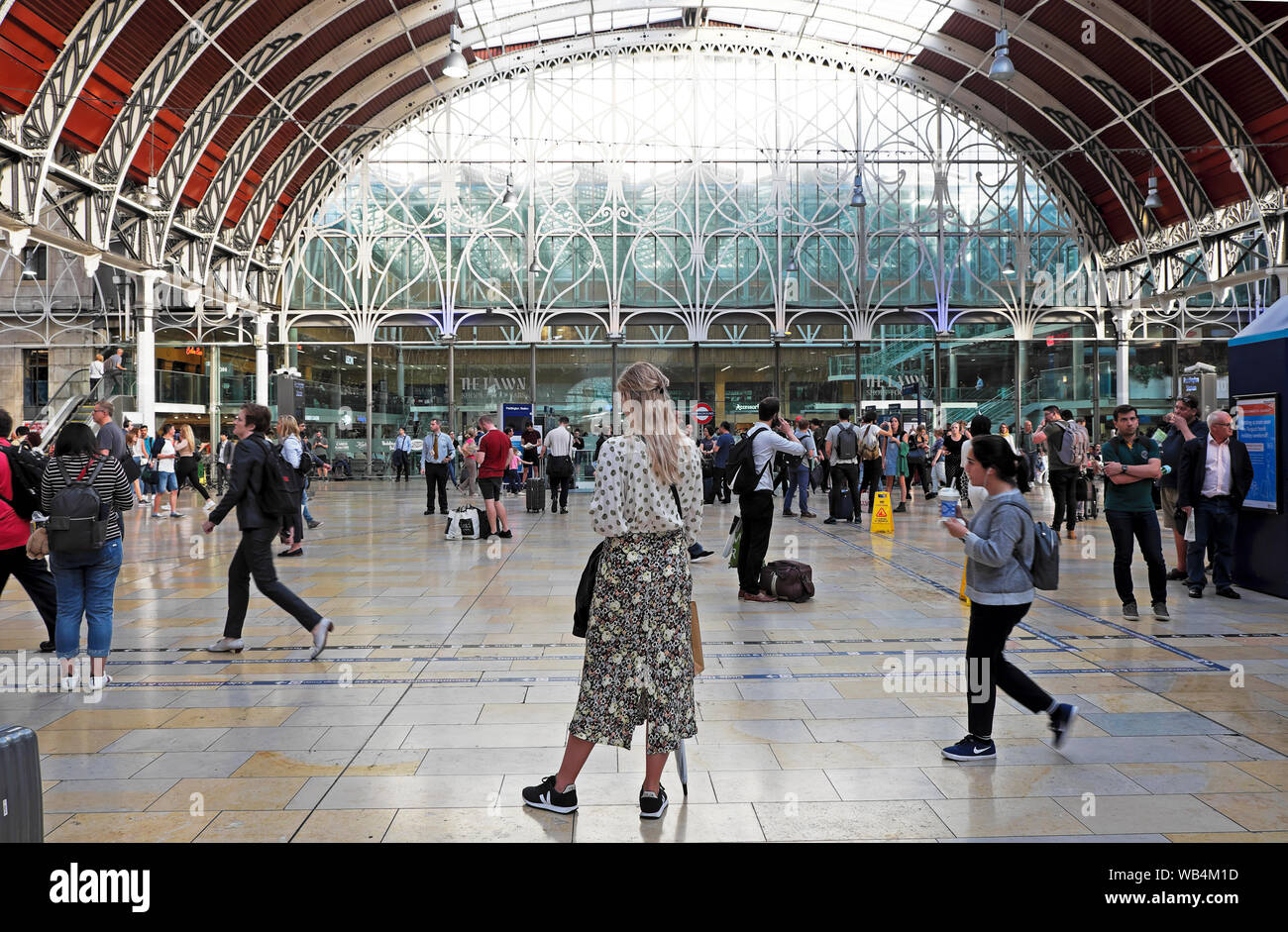 Vista posteriore di gente giovane donna in elegante moda estate gonna in piedi in attesa a Paddington Station stazioni Londra Inghilterra UK KATHY DEWITT Foto Stock