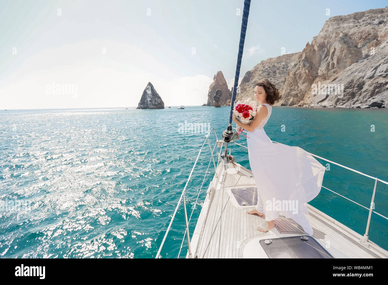 Bianco con yacht a vela va impostata lungo l'isola in una giornata calda. Il mare blu, blu cielo. La Crimea. a bordo di una giovane coppia in amore. la sposa e lo sposo. weddin Foto Stock