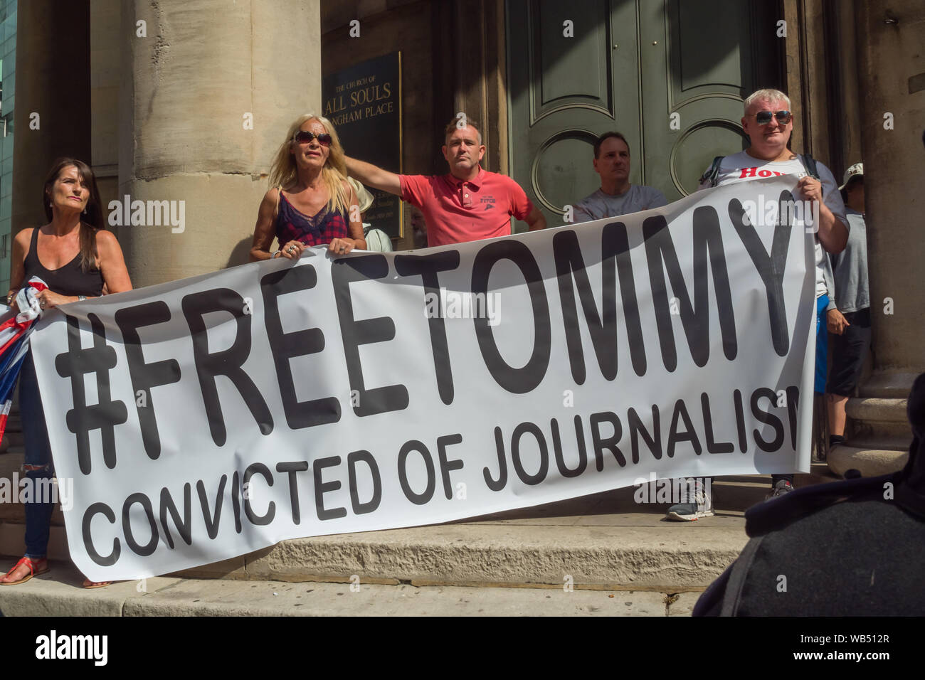 Londra, Regno Unito. 24 Ago, 2019. Tommy Robinson sostenitori tenere un banner '#FreeTommy condannati per il giornalismo' sui passi di tutte le anime. Egli è stato condannato a 9 mesi per 3 reati al di fuori di Leeds Crown Court che potrebbe aver causato il crollo di una toelettatura pista di prova e ha precedenti condanne per violenza, finanziari e frodi in materia di immigrazione, del possesso di droga e di ordine pubblico reati. La polizia ha mantenuto la due gruppi separati. Robinson sostenitori sono stati successivamente unite dai dimostranti da Trafalgar Square, e un gruppo di grandi dimensioni dal supporto fino al razzismo è venuto per unire Antifa. Credito: Peter Marshall / Alamy Live News Foto Stock