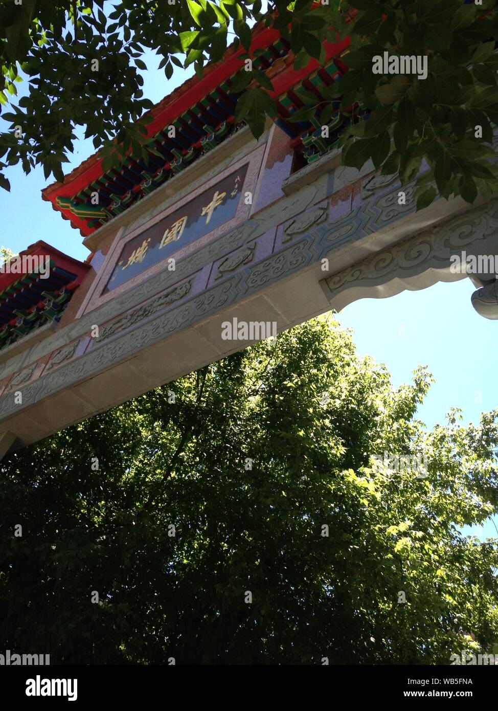 Immagine di primo piano verticale ad angolo basso del cancello di ingresso di Chinatown circondato da alberi Foto Stock