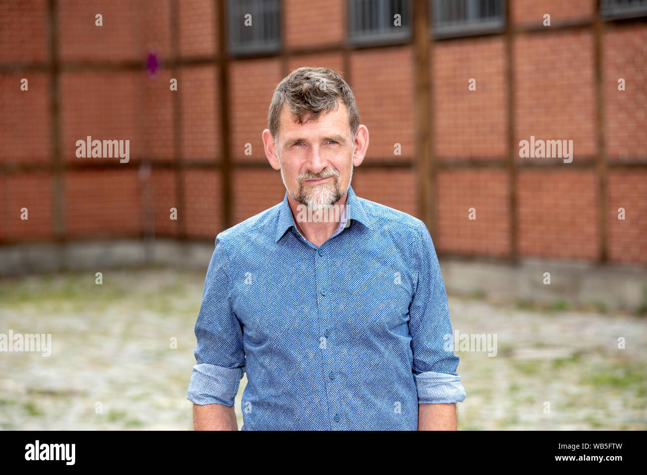 Ritratto di uomo bello nella sua 50s in maglietta blu in piedi al di fuori Foto Stock