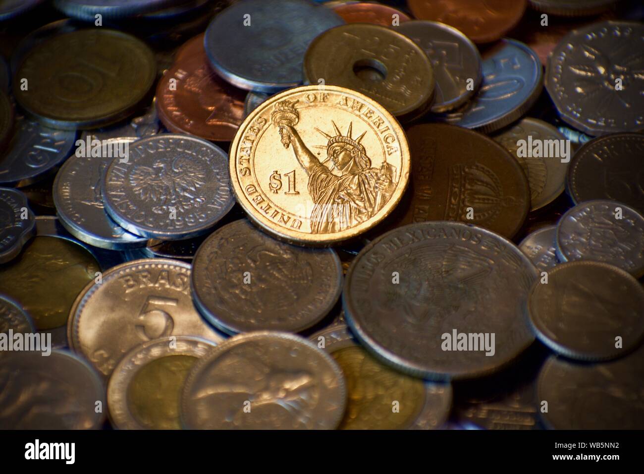 Oro americano dollar brilla sulla parte superiore della pila di sordo monete provenienti da altre nazioni. Economia forte nel mezzo di guerre commerciali. Foto Stock