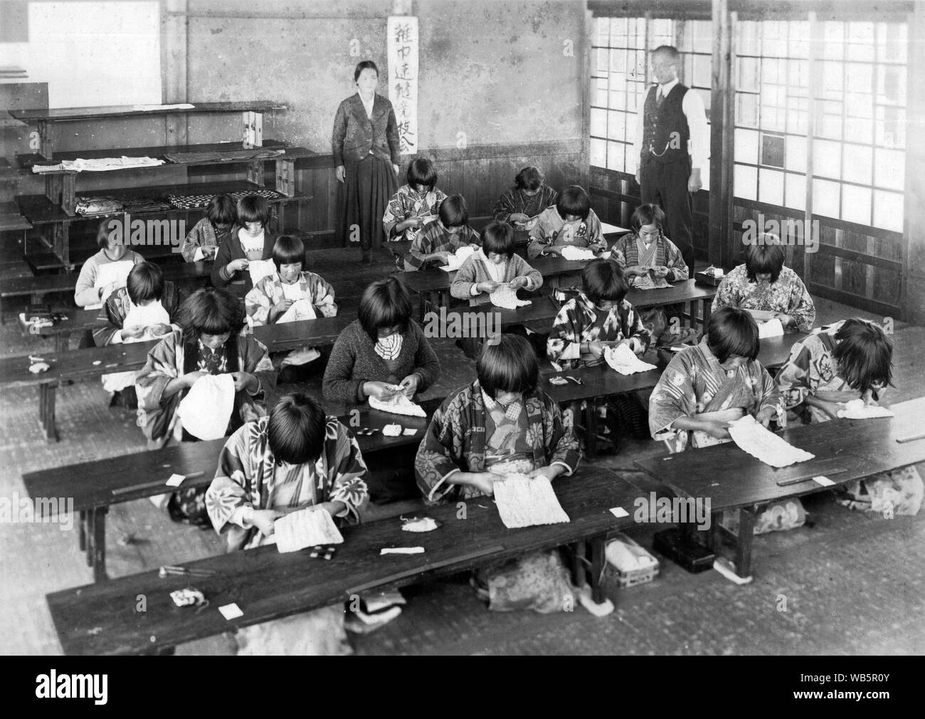 [ 1930 Giappone - Gli studenti della scuola elementare ] - femmina giapponese i bambini delle elementari in una classe sono la cucitura in classe mentre i loro due insegnanti a guardare. c1920s o 1930s. Xx secolo gelatina vintage silver stampa. Foto Stock