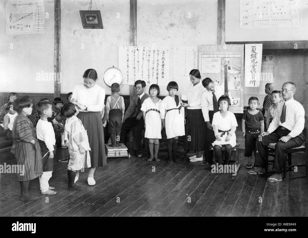 [ 1930 Giappone - Gli studenti della scuola elementare ] - Giapponese i bambini delle elementari di ottenere un health-check in una classe che sembra essere utilizzata per l'istruzione musicale. c1920s o 1930s. Xx secolo gelatina vintage silver stampa. Foto Stock